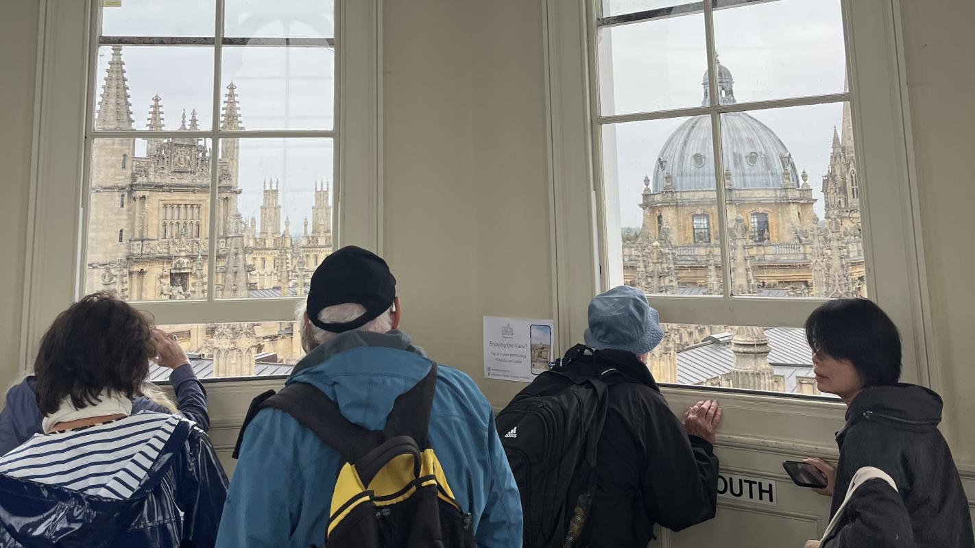 A group of visitors looks out of the cupola window at Oxford's skyline