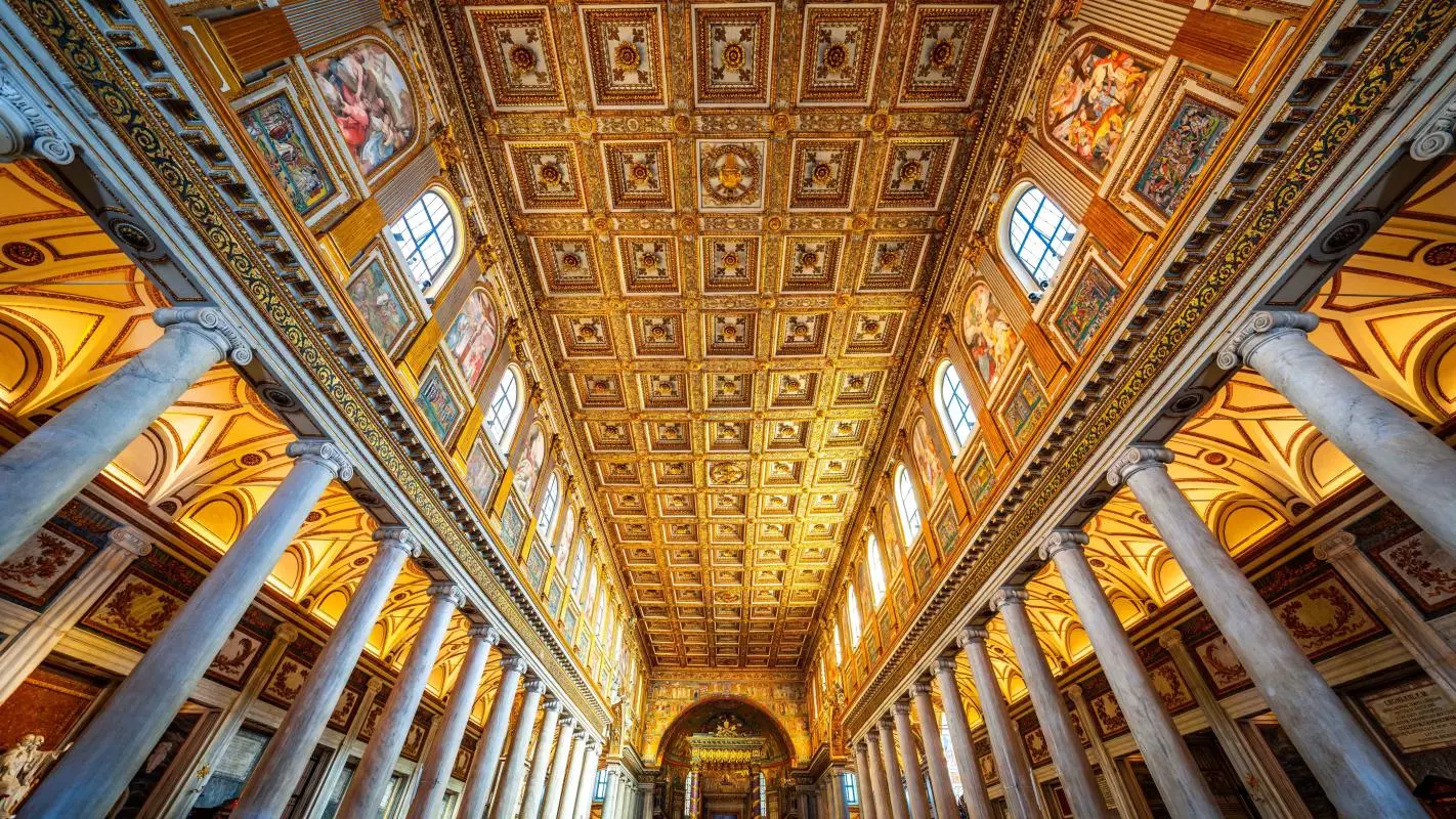view looking up of an ornate golden ceiling with with columns running down to the floor
